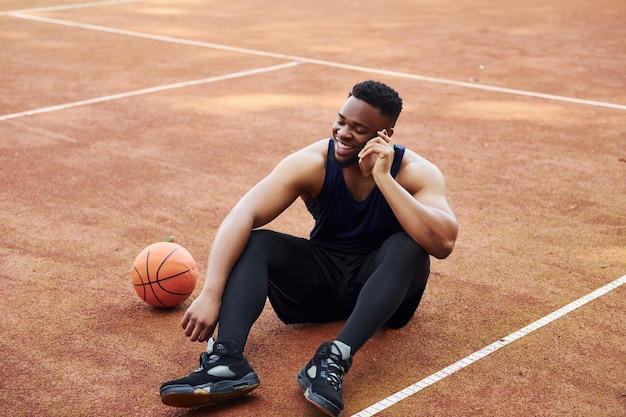 Gespräche per Telefon Afroamerikaner spielt Basketball auf dem Platz im Freien