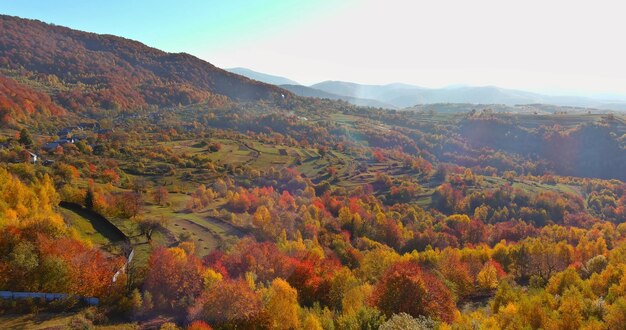 Gestalten Sie ein kleines Dorf in einer bergigen Gegend an einem Herbstmorgentag landschaftlich