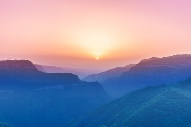 Gestalten Sie mit Bergen und Himmel im Sonnenuntergang landschaftlich