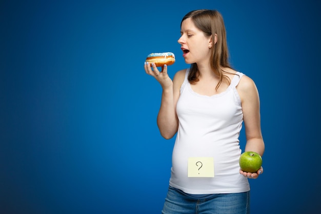 Gestante com rosquinha e maçã verde, conselhos sobre quais produtos comer. estilo de vida saudável na época perinatal.