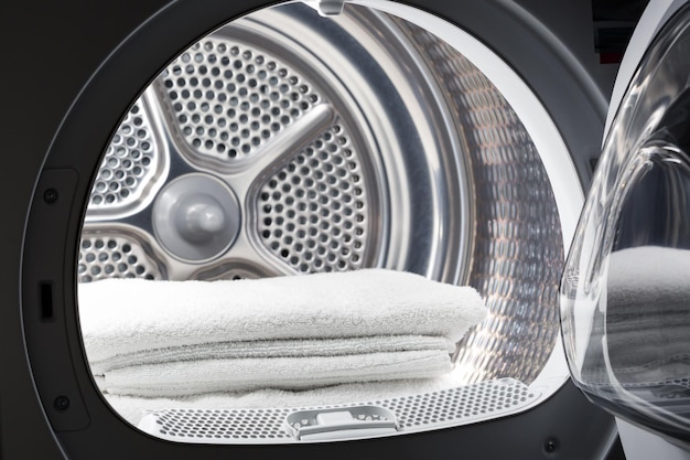 Gestapelte saubere weiße Handtücher in der Waschmaschinentrommel Sauberes Konzept Wäscherei