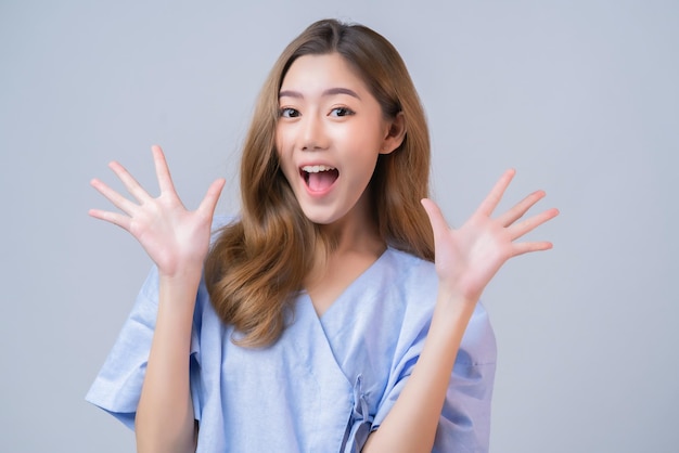 Gestenhandhaltungsglück asiatische Frau in der Krankenhausuniform, die mit fröhlichem mit guter Unterstützung und weißem Hintergrund des gut gesunden Versicherungsgeschäftsideen-Konzeptes lächelt