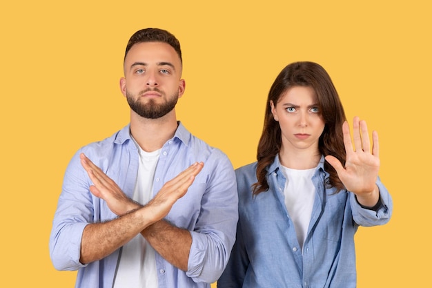 Foto gestikulierende männer und frauen hören auf, verleugnung oder ablehnung auf gelbem hintergrund zu zeigen