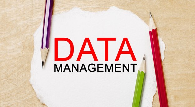 Gestión de datos de texto en un bloc de notas blanco con lápices en un espacio de madera