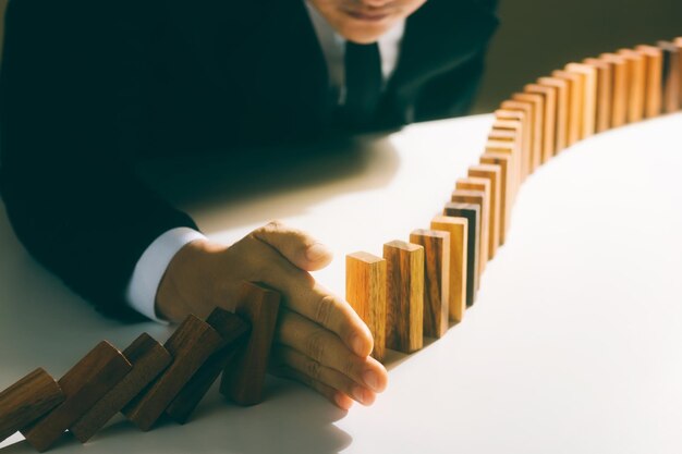 Foto gestión de riesgos hombre de negocios mano detener la caída continua de las fichas de dominó de madera detener el impacto de la crisis de los negocios cobertura resolver problemas de negocios para el éxito