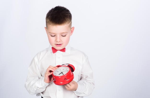 Gestión del tiempo Niño de la mañana con reloj despertador Tiempo para relajarse niño de esmoquin Infancia feliz niño feliz con reloj retro en corbata Tiempo de fiesta Empresario Ropa formal espacio de copia Multimillonario