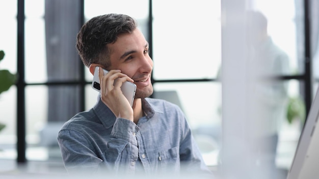 Gestionar los riesgos y recompensas a un joven empresario hablando por teléfono mientras escribe en su escritorio