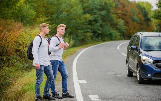 Gesto de autostop Comience una gran aventura en su vida haciendo autostop Amigos de la compañía viajeros haciendo autostop en el fondo de la naturaleza de la carretera Viajeros en camino Amigos autoestopistas que viajan