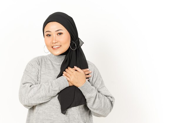 Gesto de amor próprio com as mãos no peito de uma linda mulher asiática usando um hijab isolado no fundo branco