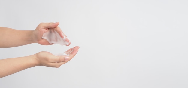 Gesto de lavagem das mãos com espuma de sabão para as mãos e bolhas em fundo branco.