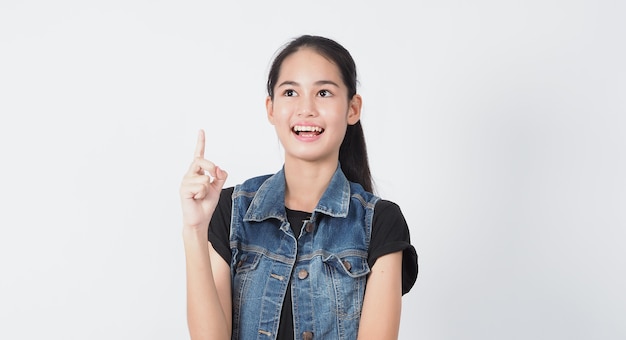 Gesto de mulher jovem asiática posando em fundo branco. representam alegre e confiante. Mostrando gestos como mini coração Ok Polegar para cima ou apontar. Jaqueta jeans surpresa espantada e feliz.