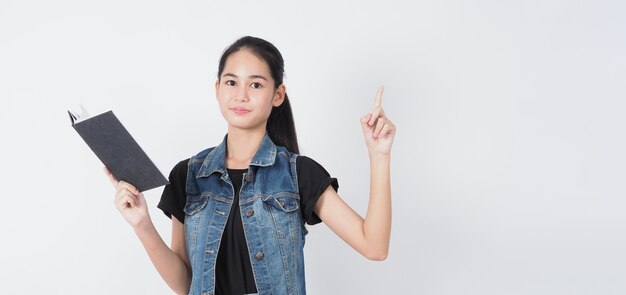 Foto gesto de mulher jovem asiática posando em fundo branco. representam alegre e confiante. mostrando gestos como mini coração ok polegar para cima ou apontar. jaqueta jeans surpresa espantada e feliz.