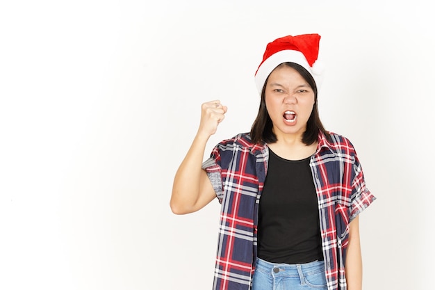 Gesto enojado de hermosa mujer asiática con camisa a cuadros roja y gorro de Papá Noel aislado en blanco