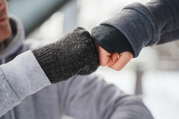 Gesto de golpe de puño entre dos amigos que usan guantes calientes durante el entrenamiento de invierno