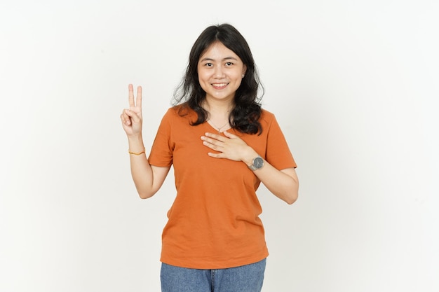 Gesto de juramento de hermosa mujer asiática vistiendo camiseta naranja aislado sobre fondo blanco.