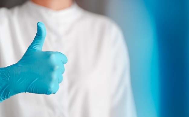 Gesto de la mano del médico con guantes azules, firme para siempre