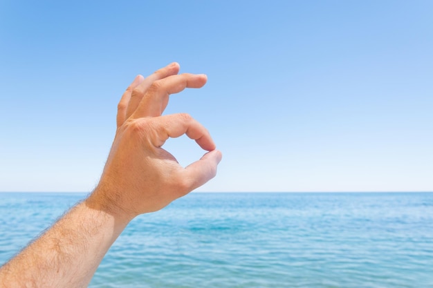 Un gesto de la mano OK frente al mar el océano Resto concepto despreocupado