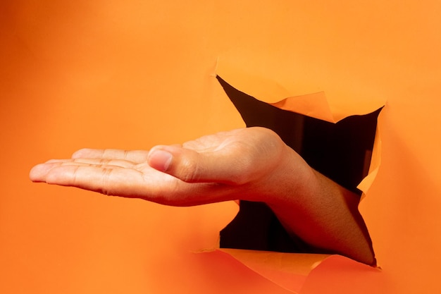 gesto de la mano sobre fondo de papel naranja rasgado