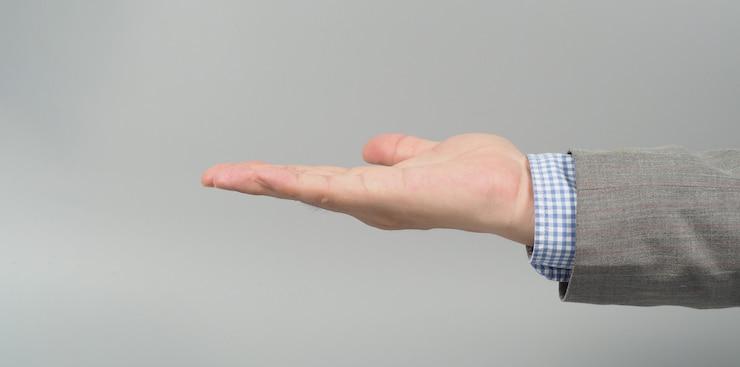 Foto gesto de la mano vacía en traje gris sobre fondo gris. tema de empresario. cerrar fotos y disparos de estudio.