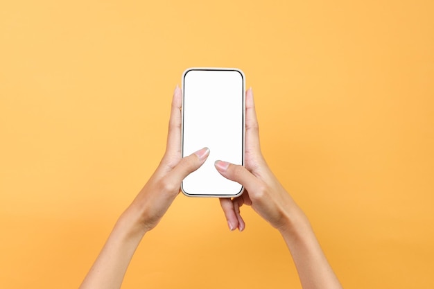 Gesto de las manos escribiendo en pantalla blanca en blanco Smartphone para Mockup aislado en fondo amarillo