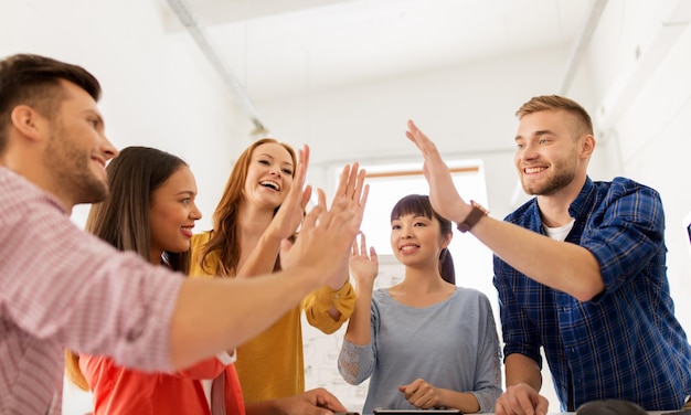 Gesto de negocios personas y concepto de trabajo en equipo equipo creativo feliz dando un alto cinco en la oficina