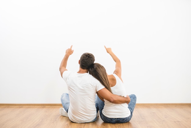 El gesto de pareja sentada en el fondo de la pared blanca