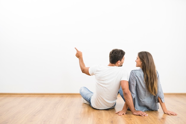 El gesto de pareja sentada en el fondo de la pared vacía