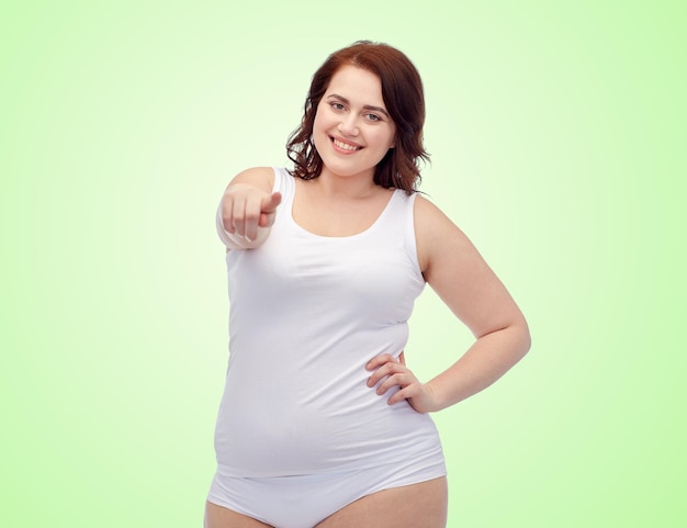 gesto, perda de peso e conceito de pessoas - sorrindo jovem mulher plus size em cueca apontando o dedo para você sobre fundo verde natural