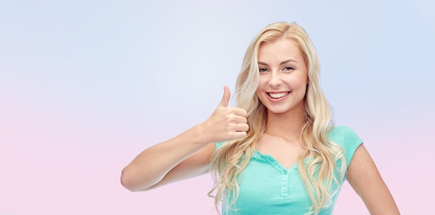 gesto positivo e conceito de pessoas - jovem sorridente ou adolescente mostrando polegares para cima sobre fundo rosa