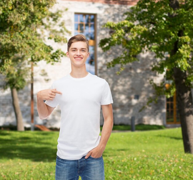 gesto, publicidade, férias de verão, educação e conceito de pessoas - jovem sorridente em camiseta branca em branco apontando o dedo sobre si mesmo sobre o fundo do campus