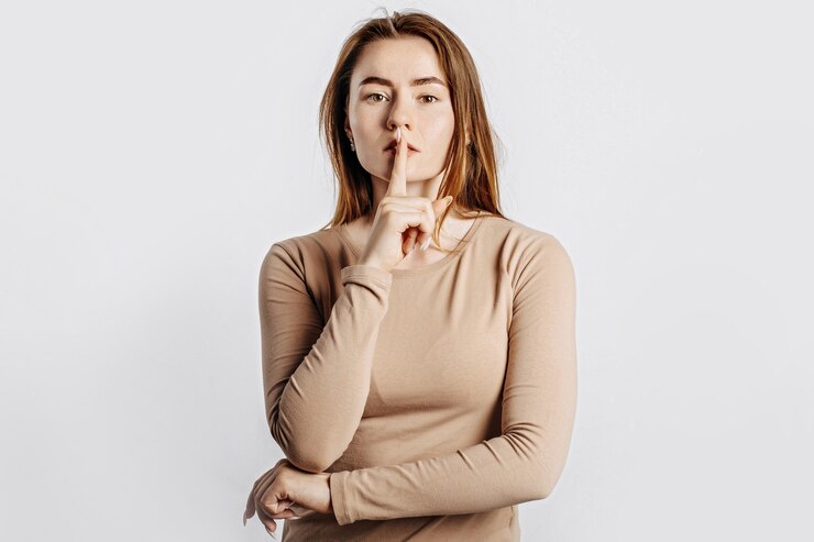 Foto gesto de shh. joven hermosa chica seria sosteniendo un dedo a los labios sobre un fondo blanco aislado