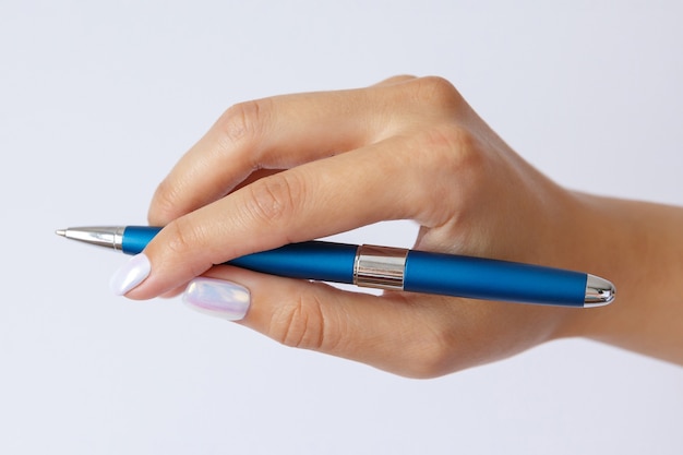 Gesto y signo, mano femenina sosteniendo lápiz azul metálico sobre blanco