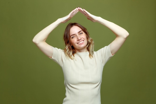 Gesto del techo de la casa amable mujer sonriente mostrar la azotea sobre la cabeza sonriendo a la cámara seguro de vida