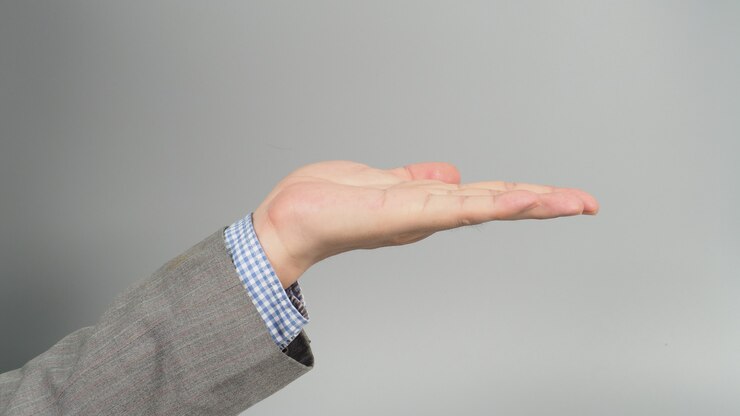 Foto gesto vacío de la mano izquierda en traje gris sobre fondo gris. tema de empresario