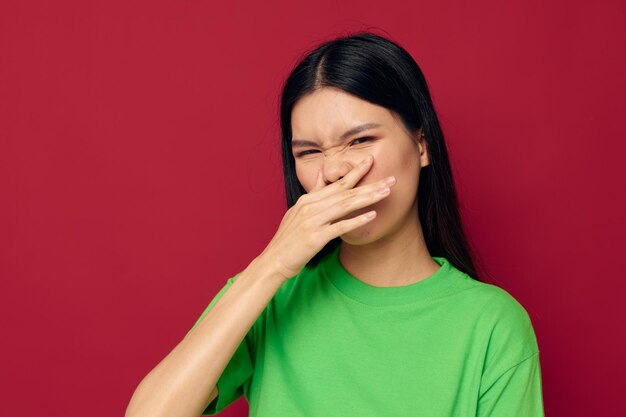 Gestos de camiseta verde de uma jovem asiática encantadora com seu modelo de estúdio de mãos inalterado