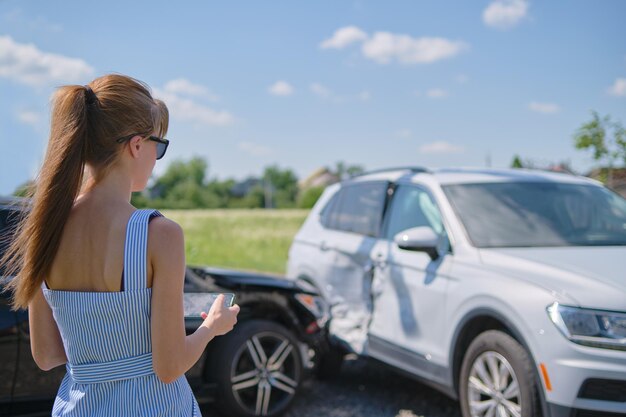 Gestresste Fahrerin, die nach einem Autounfall schockiert auf der Straßenseite steht Verkehrssicherheits- und Versicherungskonzept