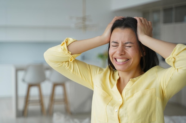 Gestresste Frau, die den Kopf mit geschlossenen Augen hält, wird zu Hause wütend und nervös Prämenstruelles Syndrom