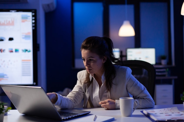 Gestresste Geschäftsfrau, die den Gewinn überprüft, steht spät in der Nacht im Büro