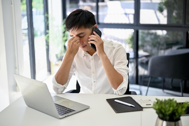 Gestresster Geschäftsmann, der mit seinem Arbeiter telefoniert und die Probleme telefonisch behebt