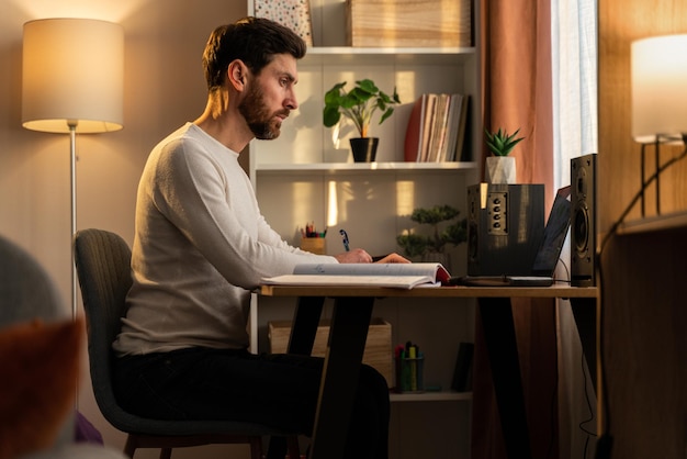 Gestresster männlicher Unternehmer, der Probleme bei der Arbeit hat. Ernster kaukasischer Mann, der zu Hause mit Laptop am Schreibtisch sitzt und auf den Bildschirm schaut