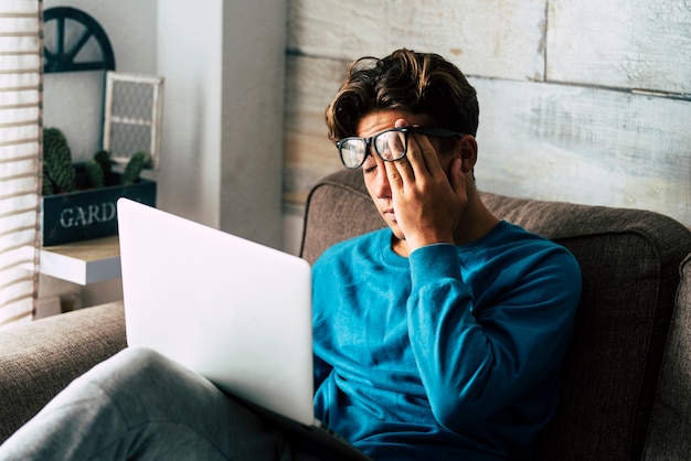 Gestresster Student zu Hause, der mit einem persönlichen Laptop lernt