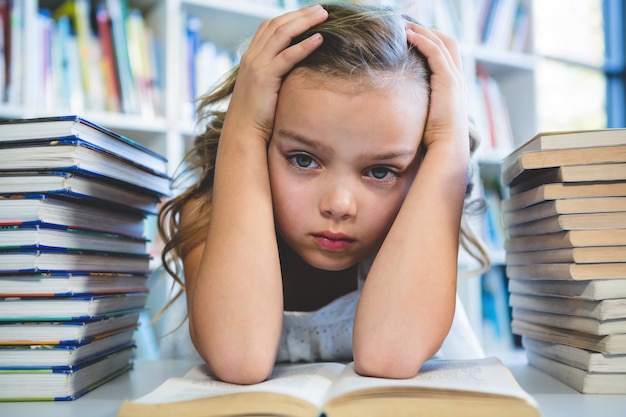 Gestresstes Mädchen mit Kopf in der Hand an der Schulbibliothek