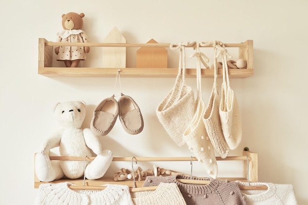 Gestrickte Kinderkleidung auf Kleiderbügel Jacke Pullover Hut Schuhe Spielzeug Kinderzimmer Kindergarten