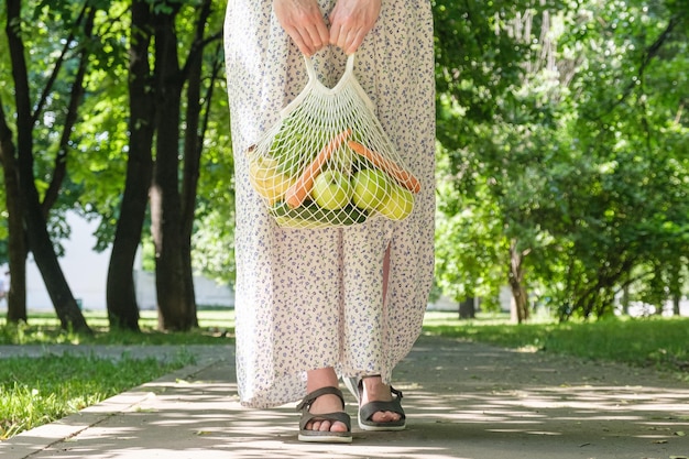 Gestrickte Netztasche mit Gemüse und Obst in den Händen einer Frau