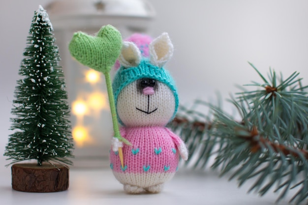 Gestrickter Hase mit Geschenken auf Holzhintergrund mit einem Weihnachtsbaum Neujahr des Hasen 2023 handgefertigt