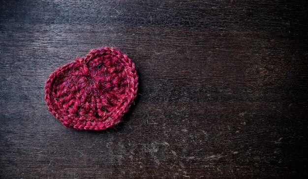 Gestricktes rotes Herz. Hintergrund für den Valentinstag. Holzmuster. Retro-Stil.