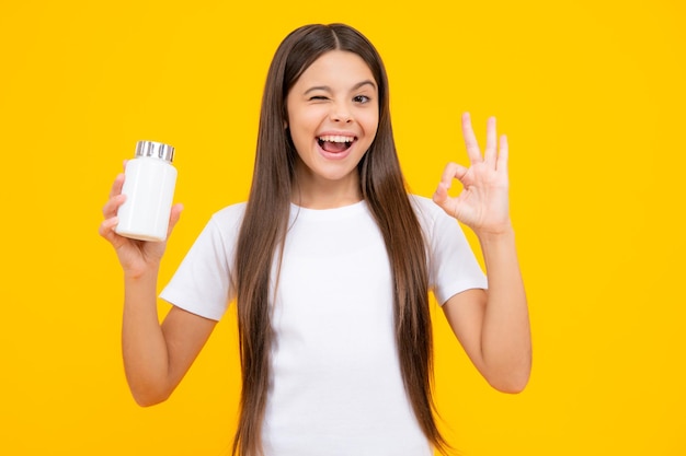Gesund bleiben Teenager-Mädchen mit Vitaminpillen auf gelb isoliertem Hintergrund Aufgeregter Teenager froh erstaunt und überglücklich Emotionen
