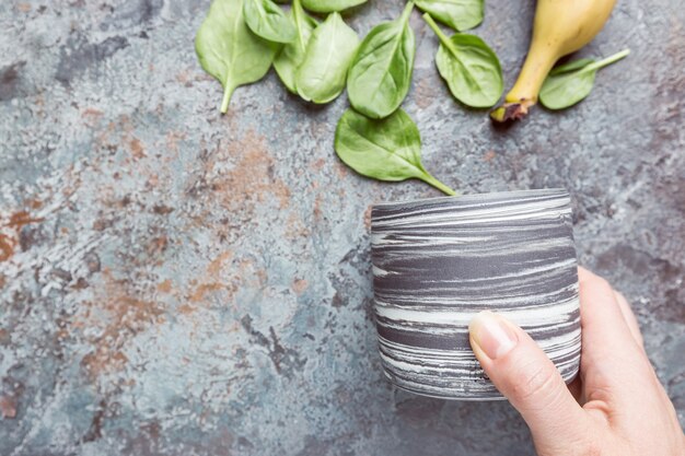 Gesund fallen die Zutaten für grünen Smoothie in die Tasse auf der Draufsicht des grauen Steinhintergrundes