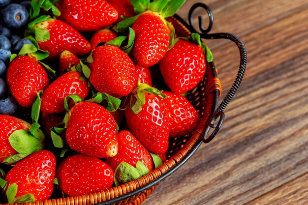 Gesunde Beeren und Erdbeeren in einem hölzernen Hintergrund des Korbes