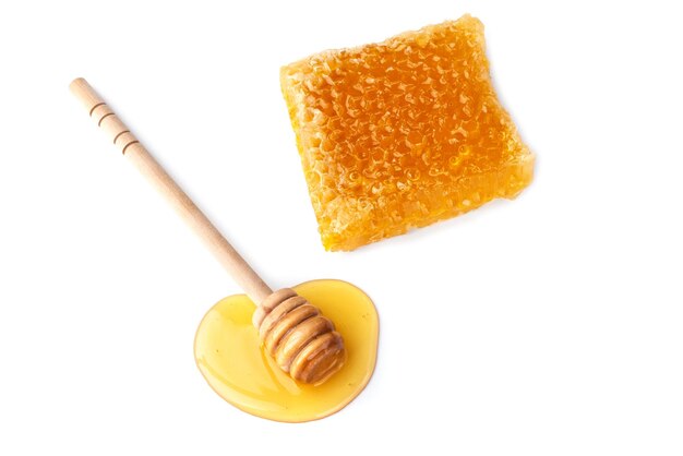 Gesunde Bio-Honigscheiben aus Waben und Holzhonigschöpflöffel isoliert auf weißem Hintergrund